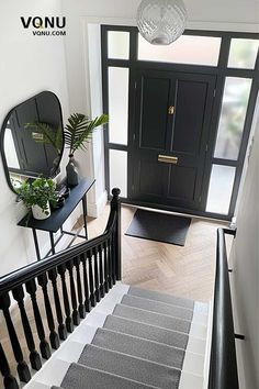 an entryway with stairs, mirror and plants