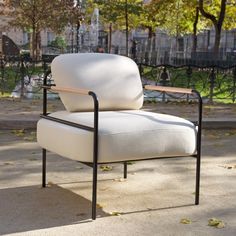 a white chair sitting on top of a cement floor next to a metal frame and tree