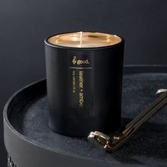 a black candle sitting on top of a table next to a golden key and bottle opener