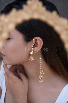 The gold-plated kundan jhumkis are traditionally inspired by the rich Indian Heritage of jewelry making. The design of the bridal jhumkis earrings features pearl hangings and a top encrusted with kundan. These ethnic jhumkis have a gold-plated pearl chain that gives them a delicate and elegant look. The richly traditional design is versatile and can be paired with almost anything Indian.  Closure - Push Back Handcrafted in Jammu and Kashmir  Paisley Pop travels the depths of India to learn techniques and crafts from deep down the local markets and villages. We give utmost importance to our quality and packaging. Our goal is to make sure you receive exactly what you are looking for and for your experience to be a special and memorable one. We are ready to help and advise you through your pu Gold Jewellery Bridal Indian, Simple Indian Earrings, Jhumka Designs Gold Indian, Indian Aesthetic Jewellery, Jhumka With Ear Chain, Traditional Earrings Indian Jewelry, Indian Bridal Earrings, Indian Earrings Jhumka, Indian Hoop Earrings