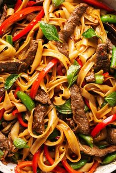 stir fried noodles with beef and peppers in a skillet, ready to be eaten