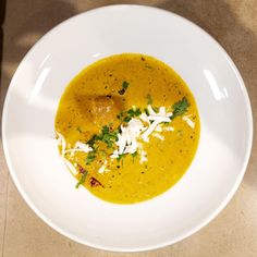 a white bowl filled with soup and garnished with parmesan on top