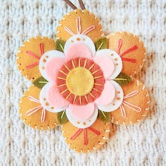 an orange and pink flower ornament sitting on top of a white blanket