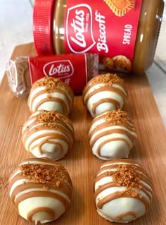 chocolate covered donuts sitting on top of a wooden cutting board next to a jar of peanut butter