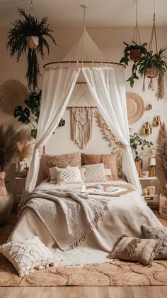 a white canopy bed sitting in a bedroom next to potted plants