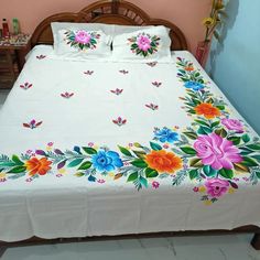 a white bed with colorful flowers and butterflies on it