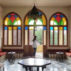 a woman standing in front of a door with stained glass windows on both sides and benches to the side