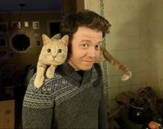 a man holding a cat on his shoulders