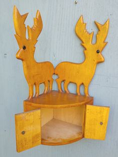 two wooden deer figurines sitting on top of a shelf