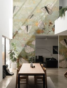 a room with a table, chairs and wallpaper on the walls that has butterflies flying over it