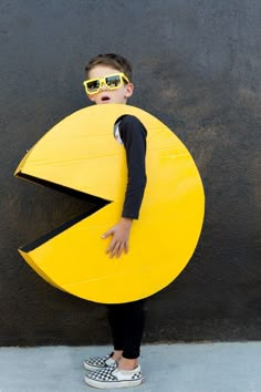 a young boy wearing sunglasses and holding a large yellow object in front of his face