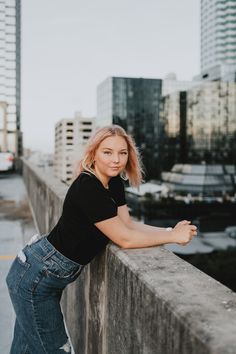 a woman leaning on the edge of a wall