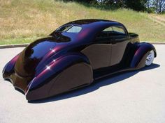 a very nice looking car parked on the side of the road with grass in the background