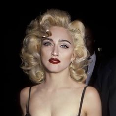 a close up of a woman with blonde hair and red lipstick wearing a black dress