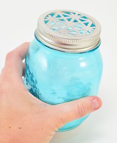 a hand is holding a blue mason jar