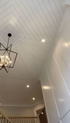 a chandelier hanging from the ceiling in a room with white walls and stairs