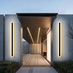 an entrance to a building with lights on the outside and wood flooring in front