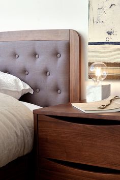 a bedroom with a bed, nightstand and painting on the wall behind it's headboard