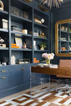 an office with blue bookcases and a wooden desk in the center is surrounded by shelves filled with books