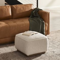 a living room with a brown leather couch and ottoman