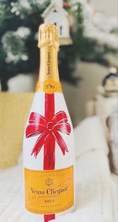 a bottle of champagne sitting on top of a bed in front of a christmas tree