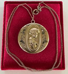 Rare and substantial antique circa 1900s Victorian era gold filled gibson girl portrait locket! This stunning pendant features a repousse woman's portrait facing to the right with ten clear paste stones, she's holding a flower with a green stone in the center. The locket hangs from its original chain. A phenomenal piece of fine Victorian jewelry, featuring a beautiful gibson girl!  ERA - Circa 1900s - Victorian  METAL / MATERIAL - Gold filled, rhinestone paste stones MARKINGS / HISTORY - Chain is marked Barrows 12k 1/15  (Barrows Jewelry is one of the oldest and most respected  jewelry stores in the country. They have been in business since 1851) CONDITION - Good antique condition. Gold filled metal has been polished & cleaned. Very little age appropriate patina & wear remains - a few mino Antique Medallion Locket Necklace Stamped 14k, Cameo Medallion Locket Necklace, Victorian Filigree Medallion Locket Necklace, Victorian Medallion Locket Necklace With Filigree, Antique Yellow Gold Medallion Locket Necklace, Victorian Style Filigree Medallion Locket Necklace, Antique Style Yellow Gold Medallion Locket Necklace, Vintage Stamped 14k Locket Necklace For Wedding, Victorian Style Medallion Locket Necklace With Filigree