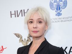 a woman with white hair standing in front of a red carpet