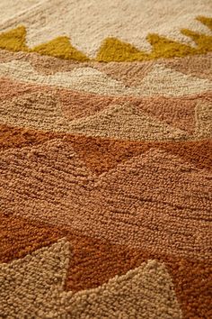 an area rug with various colors and shapes on it, including oranges, yellows, and browns