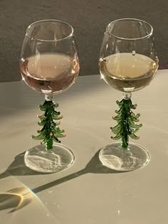 two wine glasses sitting on top of a table next to each other with christmas decorations