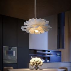 a white chandelier hanging from the ceiling over a dining room table with flowers on it