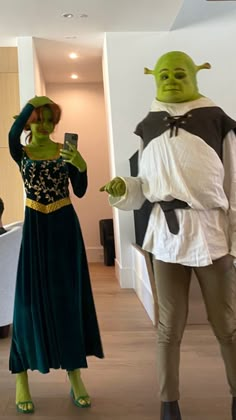 two people in costume standing next to each other on the floor with one holding a cell phone