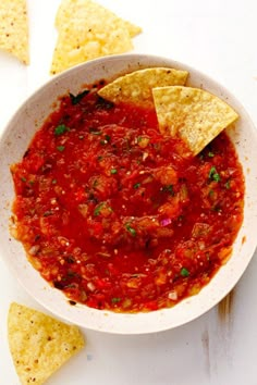 a white bowl filled with salsa and tortilla chips on top of a table