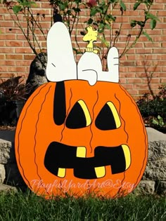 a pumpkin with a cat sitting on it's head in front of a brick wall