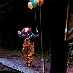 a clown is holding balloons in the air