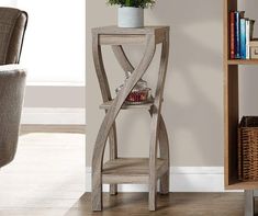 a corner table with a plant on it in front of a bookcase and chair