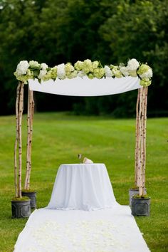 an outdoor ceremony setup with white flowers and greenery