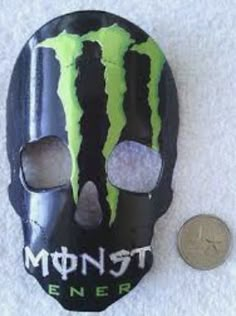 a coin is laying next to a mask with the word monster energy on it