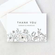 a thank card with black and white flowers on it, next to an envelope that says thank you