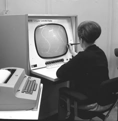 a person sitting at a desk with an old computer