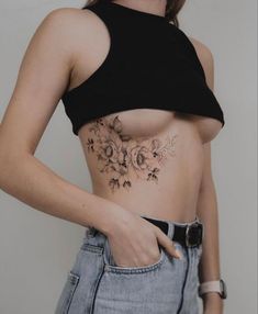 a woman with a flower tattoo on her stomach is looking at the camera while wearing jeans