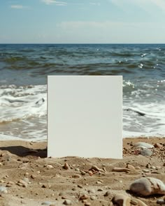 an empty white board sitting on top of a sandy beach