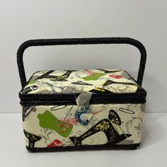 a small sewing box with handles on the front and side, decorated with images of women's shoes