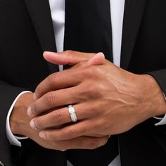 a close up of a person wearing a suit and holding his hands together