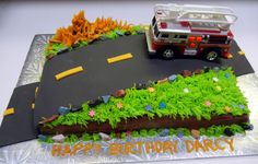 a birthday cake with a firetruck and flowers on the top is made to look like a road