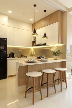 a kitchen with three stools in front of an island and two lights above it