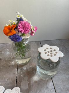 two vases filled with flowers sitting on top of a wooden table next to hearts