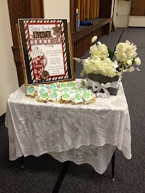 a table with some cookies on it and flowers in a vase next to the sign