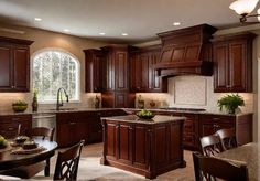 a kitchen filled with lots of wooden cabinets and counter top space next to a dining room table