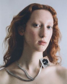 a woman with red hair wearing a necklace