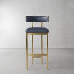 a gold bar stool with a blue upholstered seat and backrest in front of a white wall